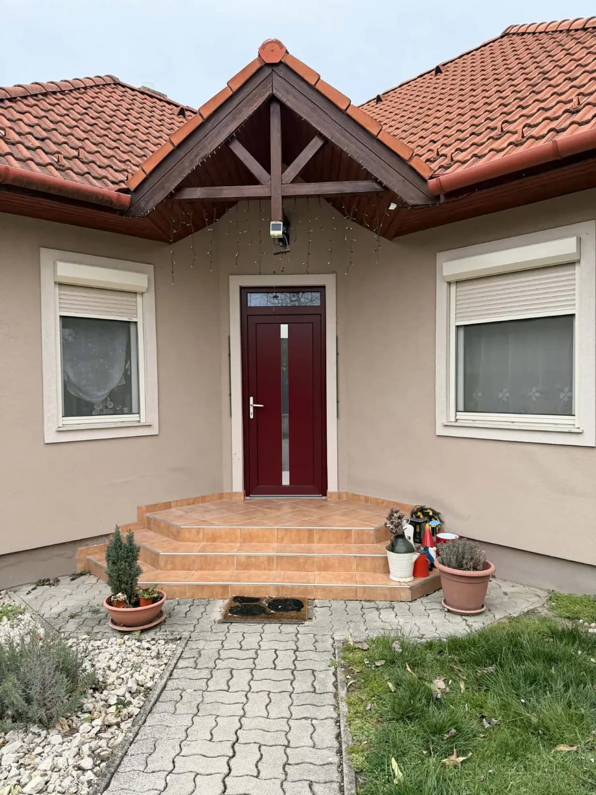 Bordó bejárati ajtó üvegbetéttel, családi ház homlokzatán