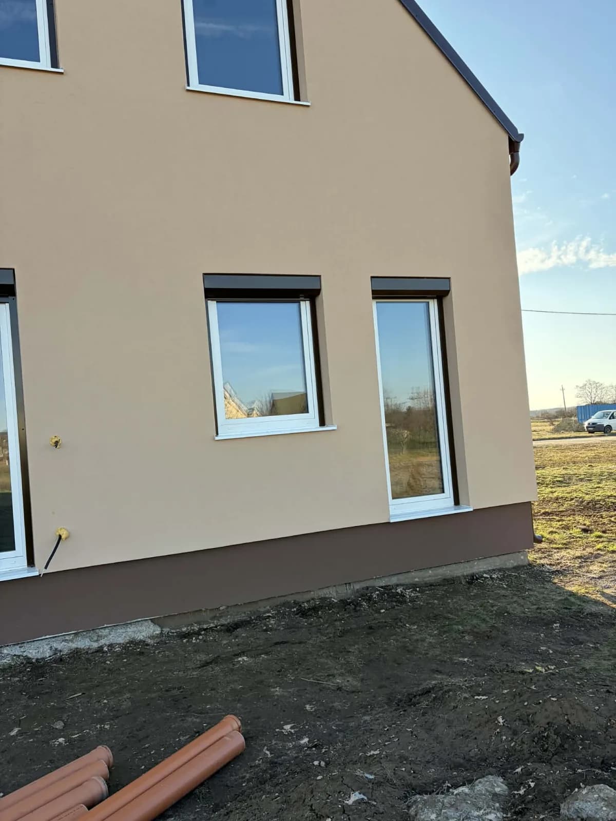 Ház sarka fehér ablakokkal és Sepia barna külső tokos redőnyökkel