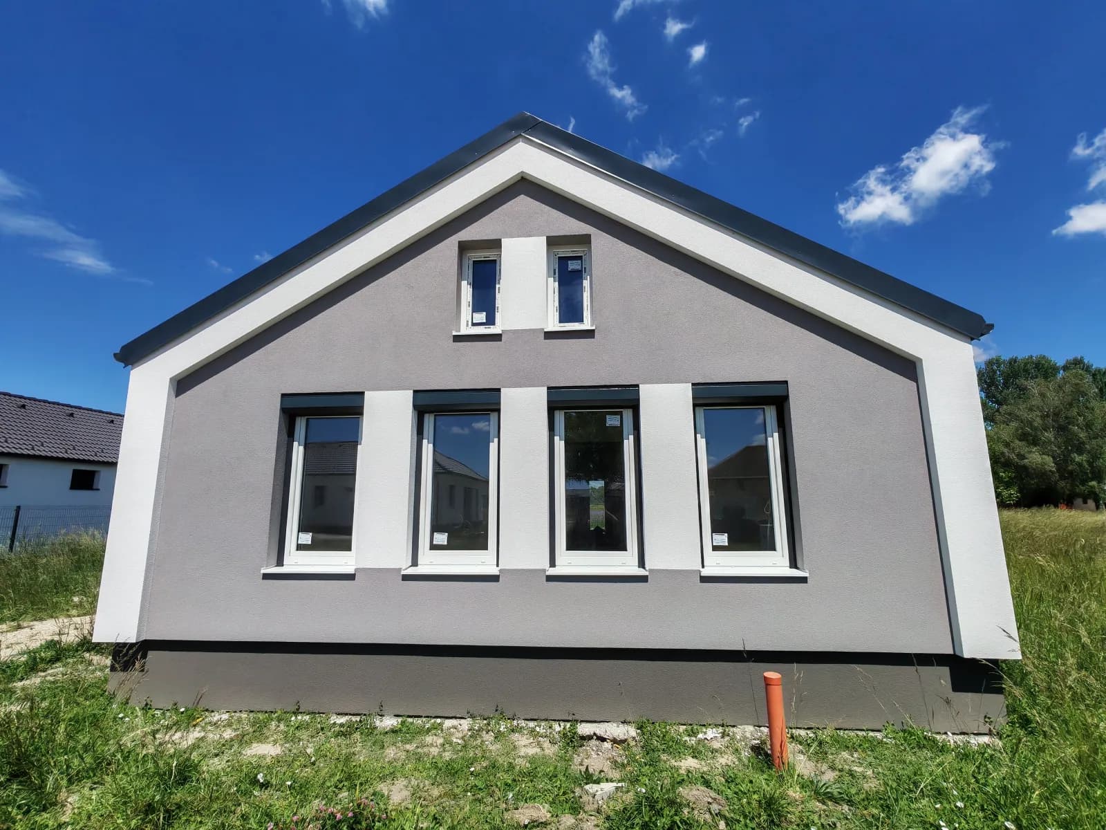 Új építésű szürke vakolt bungaló kész homlokzata fehér REHAU ablakokkal Lipóton